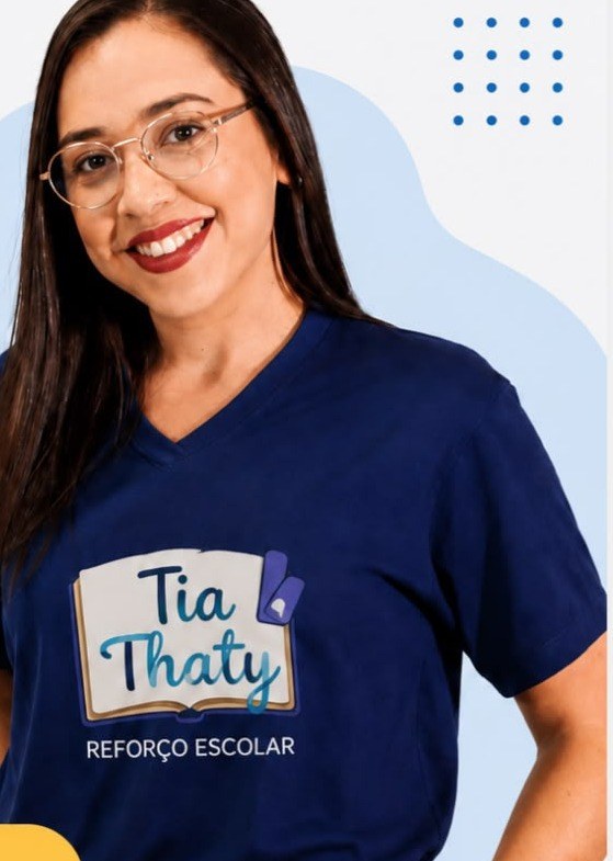Thaty, professora do reforço escolar Tia Thaty, sorrindo de óculos e camiseta azul-marinho com a logo Tia Thaty